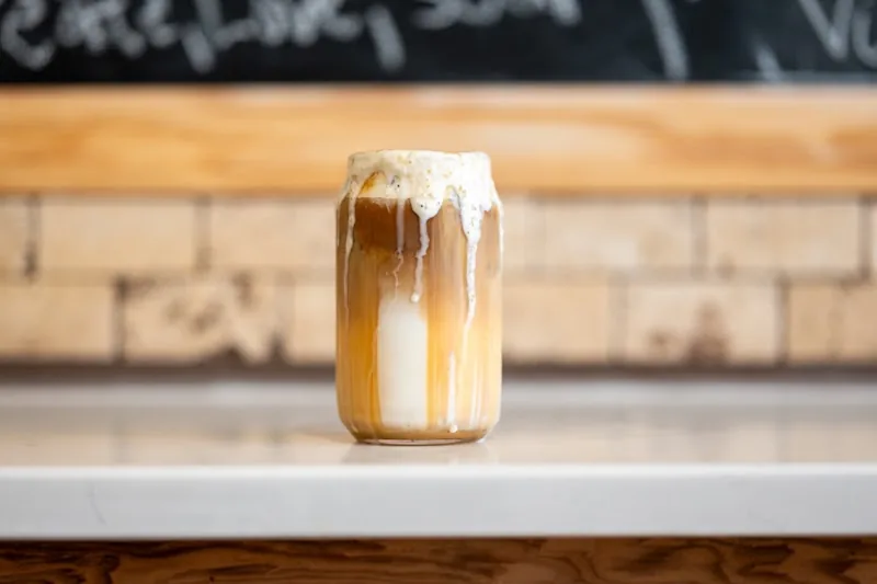 An iced latte dripping down the glass on the counter