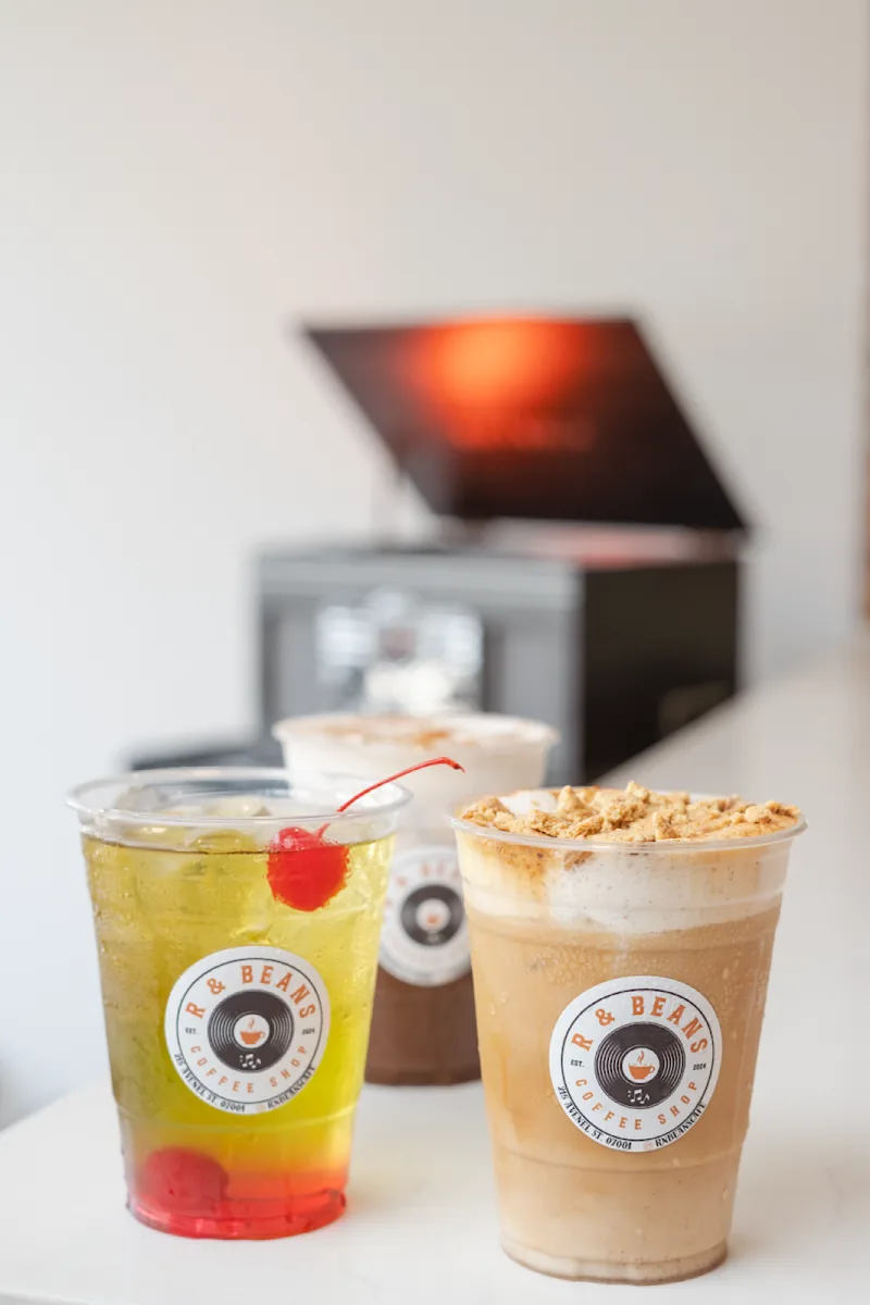 Two takeaway cups with the round R&Beans logo